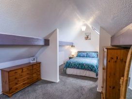 A bedroom with a bed a wooden dresser a wardrobe and a lamp at Wayside Farm Dairy Cottage in Cloughton near Burniston