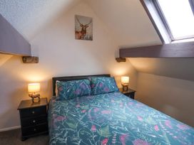 A bedroom with a double bed floral bedding two bedside tables with lamps and a skylight window at Wayside Farm Dairy Cottage Cloughton near Burniston