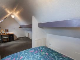 An attic bedroom with a bed, a dressing table with a mirror and stool, radiators and a sloped ceiling at Wayside Farm Dairy Cottage in Cloughton near Burniston