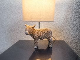 A lamp with a shade and a decorative sculpture of an animal on a reflective table surface