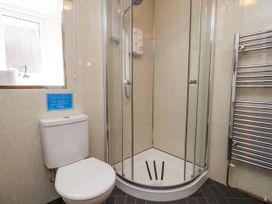 A bathroom with a toilet a corner shower unit a window and a chrome towel radiator at Wayside Farm Dairy Cottage in Cloughton near Burniston