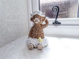 A textured figurine of a sitting highland cow with a white hat and a yellow duck on a windowsill at Wayside Farm Dairy Cottage Cloughton near Burniston