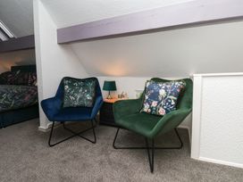 Two chairs and a bedside table in a bedroom at Wayside Farm Dairy Cottage in Cloughton near Burniston