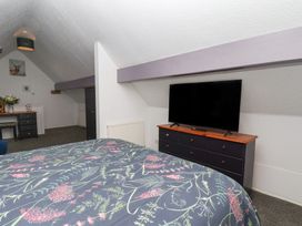 A bedroom with a bed, television, dresser and desk at Wayside Farm Dairy Cottage Cloughton near Burniston