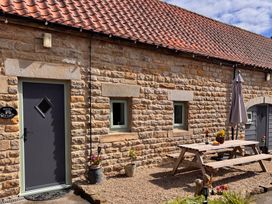 A patio area with a table and umbrella at Wayside Farm Dairy Cottage Cloughton near Burniston