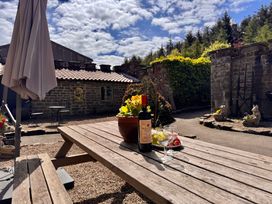A garden setting with a table, wine bottle, glasses, flowers and chairs at Wayside Farm Dairy Cottage Cloughton near Burniston