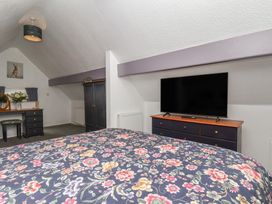 A bedroom with a bed, desk, chair, and television at Wayside Farm Stable Cottage Cloughton near Burniston