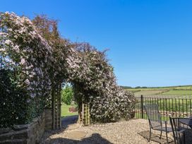 An outdoor area with flowers and a gate at Wayside Farm Cart Cottage Cloughton near Burniston
