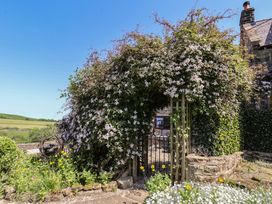 A garden with flowers and a gate at Wayside Farm Cart Cottage in Cloughton near Burniston