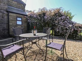 An outdoor seating area with a table and chairs at Wayside Farm Cart Cottage in Cloughton near Burniston
