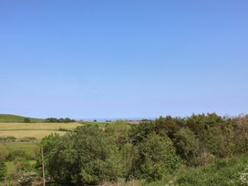 A view of fields and trees with the sea in the distance at Wayside Farm Cart Cottage Cloughton near Burniston