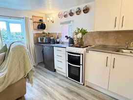A kitchen with a window, stove, fridge, and sink at Wayside Farm Cart Cottage Cloughton near Burniston