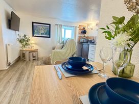 A living room with a dining table and kitchen appliances at Wayside Farm Cart Cottage Cloughton near Burniston