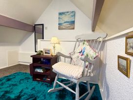 An attic with a rocking chair and small table at Wayside Farm Cart Cottage Cloughton near Burniston