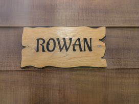 A wooden sign with the word Rowan on a wooden wall at The Rowan Pod in Cowbridge