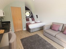 A bedroom with a bed sofa rug desk and wooden door at The Rowan Pod in Cowbridge