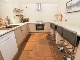 A kitchen with appliances and stools at Mill Race House Alston