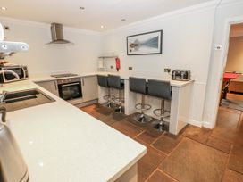 A kitchen with bar stools and kitchen appliances at Mill Race House in Alston