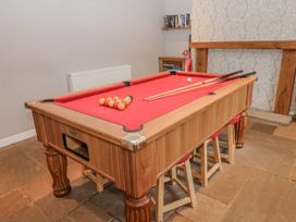 A game room with a pool table and cues at Mill Race House in Alston