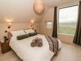 A bedroom with a bed and a large window at Twyn Isaf in Borth