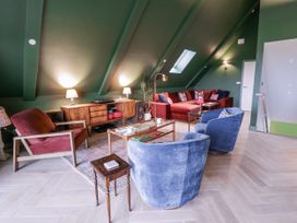 A living room with a red sofa and blue chairs at Twyn Isaf in Borth