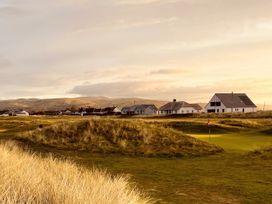 A golf course with houses and hills at Twyn Isaf Borth