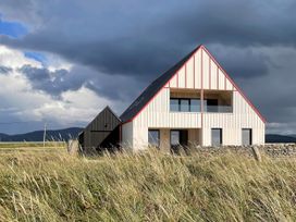 A house with windows and a roof in front of a grassy area at Twyn Isaf in Borth