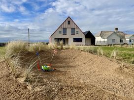 An outdoor area with sand and a house at Twyn Isaf in Borth