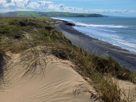A beach view with sand dunes and a pier at Twyn Isaf Borth
