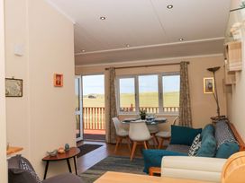 A living room with a dining area and views of grass at Boa Vista in Bacton