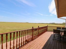 An outdoor area with a table and chairs on decking at Boa Vista in Bacton