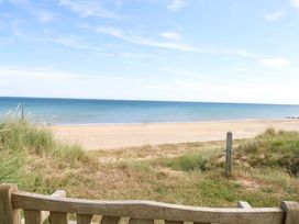 A beach with ocean view and grass near a wooden bench at Boa Vista, Bacton