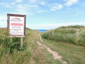 A pathway leading to the ocean with a sign at Rainbows End Chalet Park in Bacton