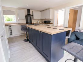 A kitchen with an island and stools at Cartref in Pen Y Ball near Holywell