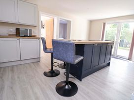 A kitchen with a bar island and stools at Cartref in Pen Y Ball near Holywell
