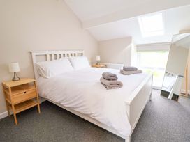 A bedroom with a bed, side table, lamp, and mirror at Cartref Pen Y Ball near Holywell