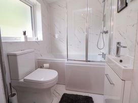 A bathroom with a bathtub, toilet, sink and window at Cartref Pen Y Ball near Holywell