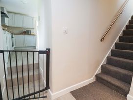 A hallway with a staircase and a kitchen at Cartref Pen Y Ball near Holywell