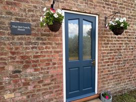 An outdoor view of The Old Coach House with a blue door at The Old Coach House at The Vicarage Mappleton near Hornsea