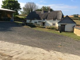 A cottage with a thatched roof and farm building at Westacombe Farm Dunsford near Tedburn St Mary