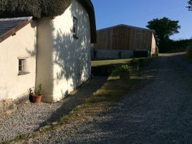 A thatched cottage and wooden barn on a gravel path at Westacombe Farm in Dunsford near Tedburn St Mary