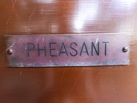 A close up of a metal nameplate with the word PHEASANT on a wooden surface at Pheasant Withern near Alford