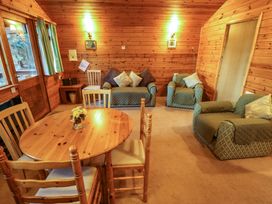 A wooden dining table with chairs and green cushioned armchairs in a wood-paneled room at Pheasant Withern near Alford