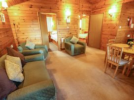 A living room with green upholstered sofa and armchair wooden walls and a dining table with chairs at Pheasant Withern near Alford