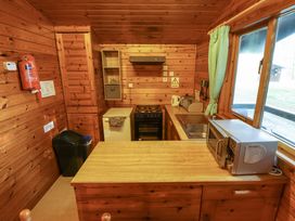 A kitchen with wooden walls and ceiling a stove a sink microwave and a refrigerator at Pheasant Withern near Alford