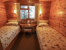 A wooden bedroom with two single beds a small desk and window at Pheasant Withern near Alford