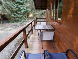 A wooden balcony with a table and chairs next to a forest at Pheasant Withern near Alford