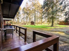 A wooden porch with a table and chairs overlooking a gravel path and trees at Pheasant in Withern near Alford