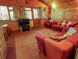 A living room with red sofas a television wooden walls and windows at Kestrel in Withern near Alford