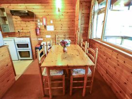 A wooden dining table with six chairs and a vase of flowers in a wooden kitchen at Kestrel Withern near Alford